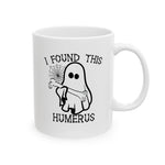 The I Found This Humerus Halloween Ghost Mug features a cartoon ghost holding a bone, complemented by a spiderweb and clever wordplay on humerus and humorous, making it an ideal coffee mug for spooky season enthusiasts.