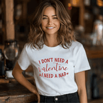 Woman wearing a white t-shirt with the funny Valentine's Day quote, "I don’t need a Valentine, I need a nap," in white script.
