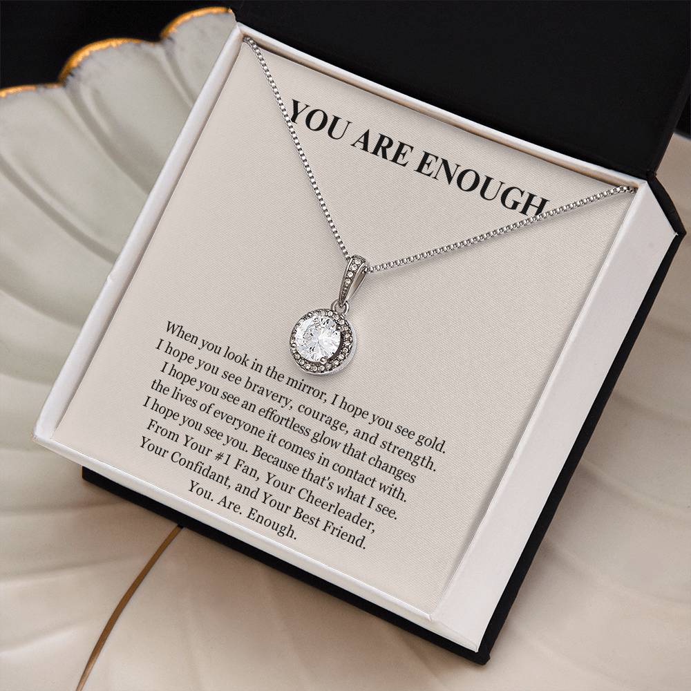 The Eternal Hope Necklace - You Are Enough features a silver round, sparkling pendant in a black and white box. The lid displays YOU ARE ENOUGH above an inspiring printed message about self-worth and inner strength.