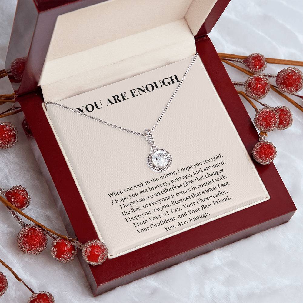 The Eternal Hope Necklace - You Are Enough features a silver round pendant in an open red jewelry box. The lid reads You Are Enough above an inspiring self-love note, with frosted red berries in the background.