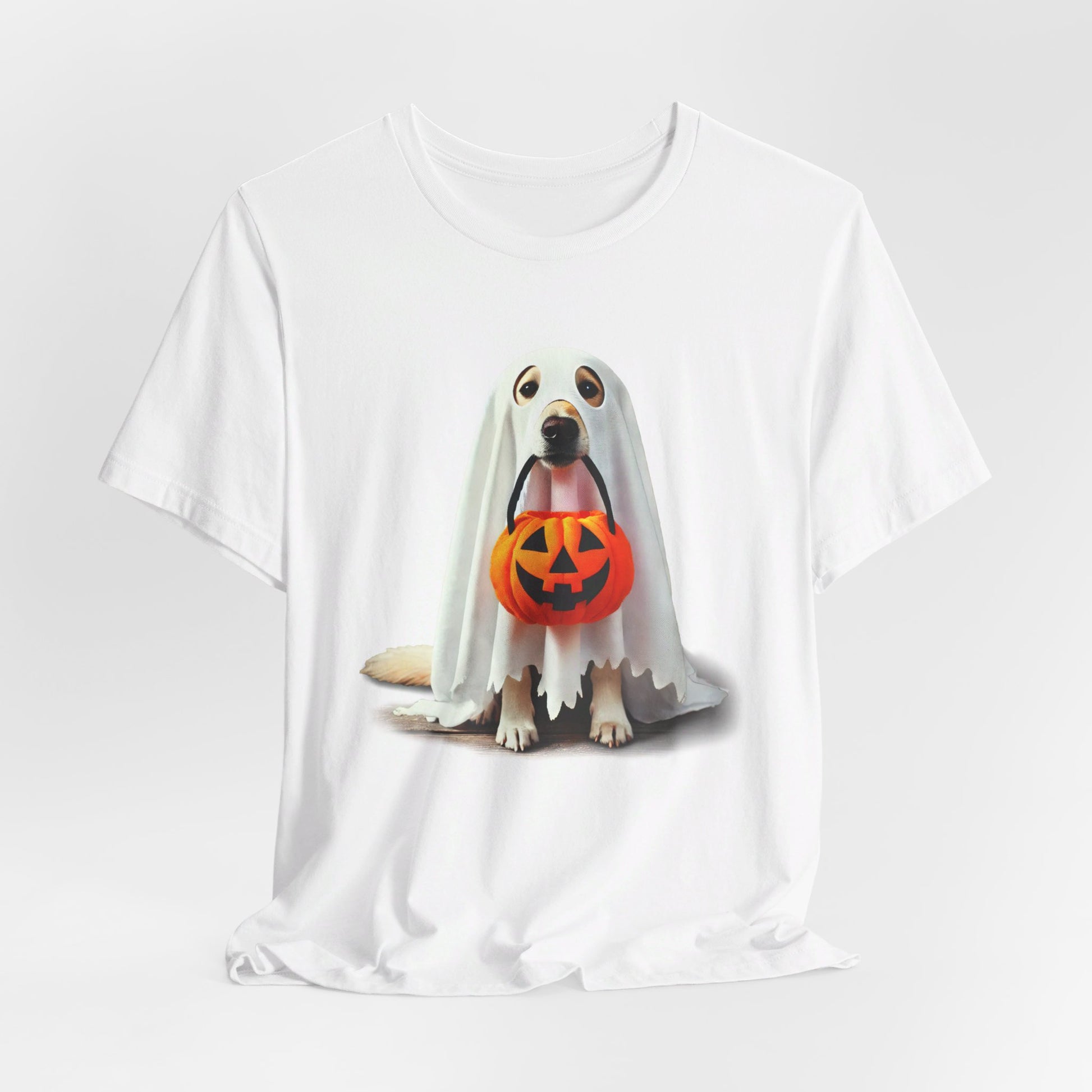 The Ghostly Pup Halloween T-Shirt, a unisex jersey short sleeve tee, showcases a ghost dog under a white sheet with a pumpkin bucket. This adorable trick-or-treat design adds spooky charm to any wardrobe with its plain background.