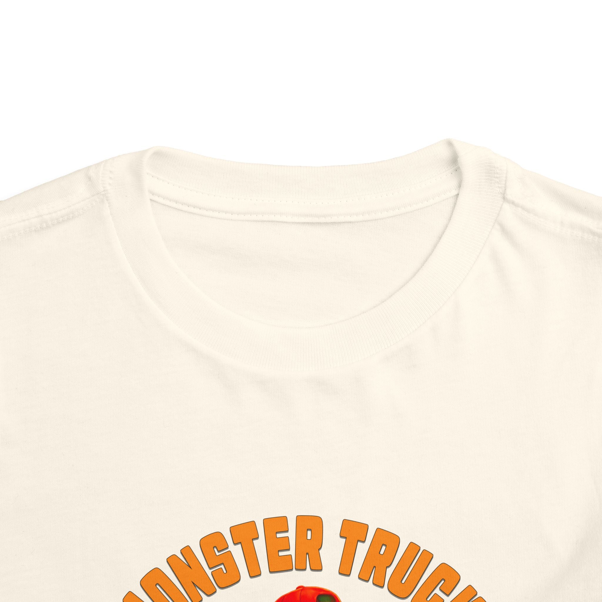 A close-up of the Monster Truck Rex T-Shirt 🛻🦕 – Toddler Boys Tee shows bold orange “MONSTER TRUCK” text. The Bella+Canvas shirt is displayed flat against a white background.