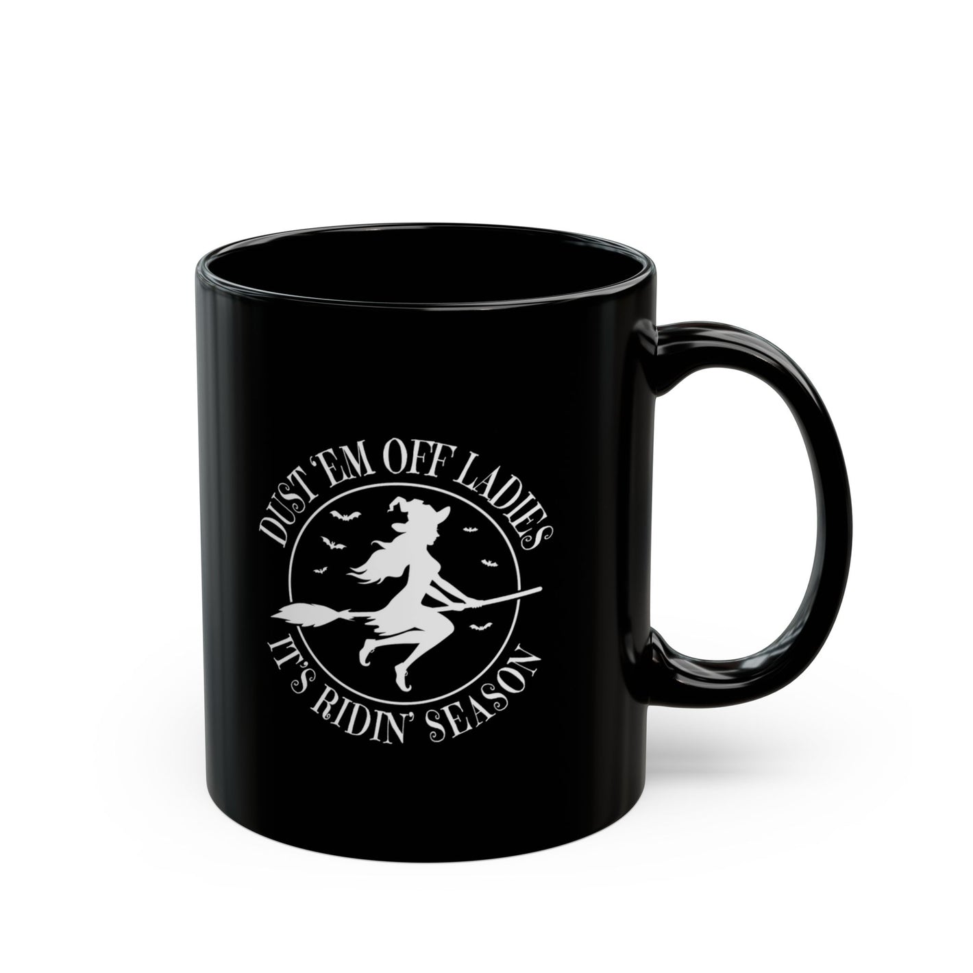 The Dust Em Off Ladies Halloween Mug is a black ceramic mug with white text featuring a witch on a broomstick and bats. It reads, Dust Em Off Ladies Its Ridin Season, perfect for those who love witchy vibes. Available in 11oz and 15oz sizes.