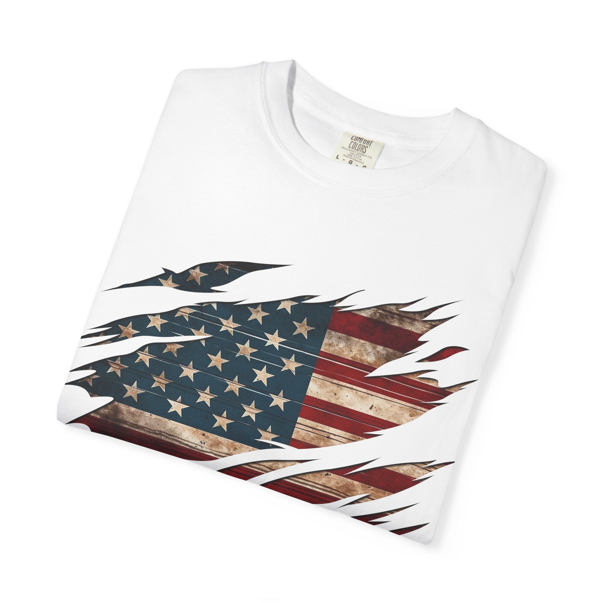 The “Torn Patriot” Distressed American Flag Comfort Colors Tee is a folded white shirt made of US cotton, featuring a distressed, ripped-effect flag graphic on the front.