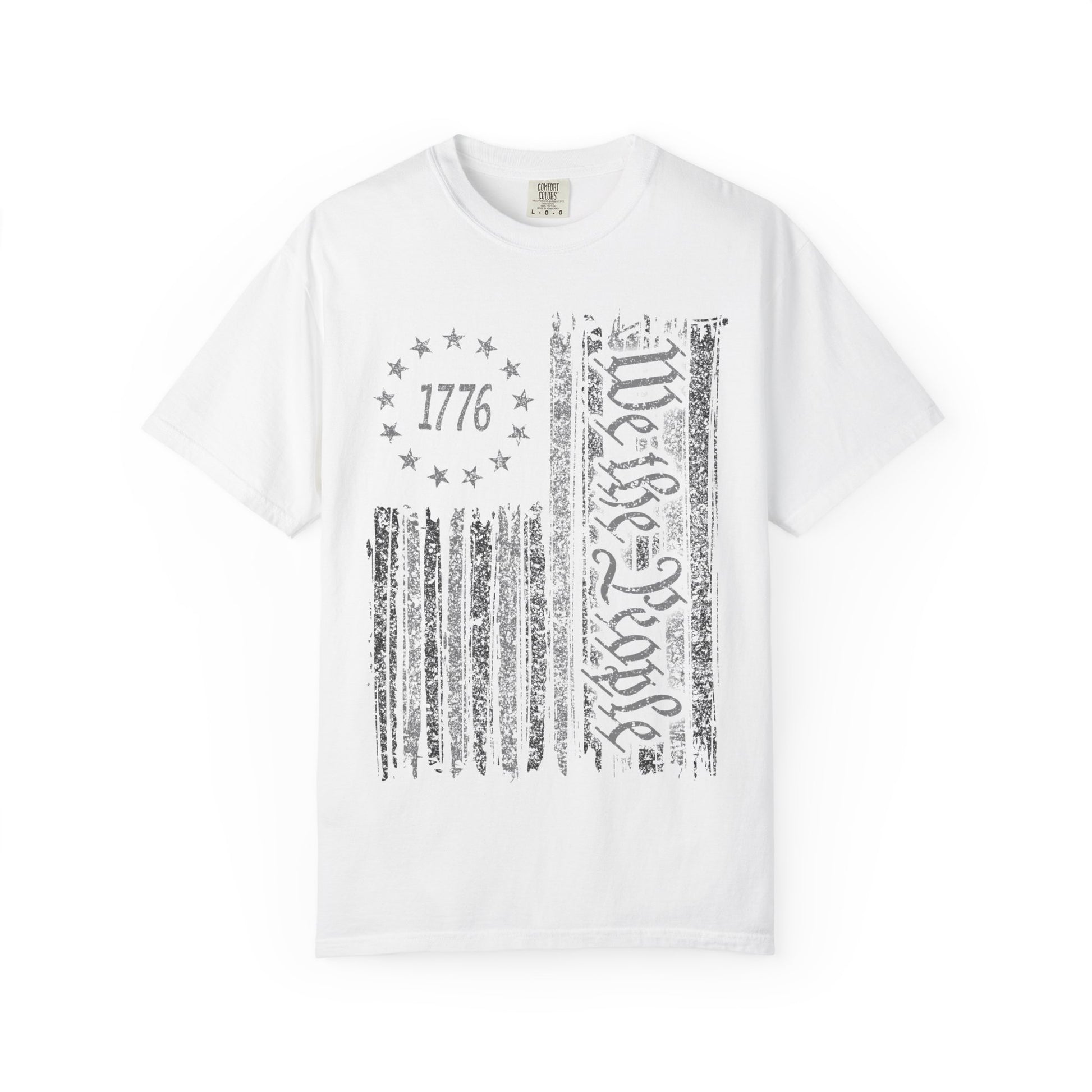 The We The People Distressed Flag Tee is a unisex white Comfort Colors 1717 shirt featuring a distressed American flag with 1776 in a circle of stars and We the People boldly on the front.