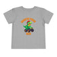 The Monster Truck Rex T-Shirt 🛻🦕 – Toddler Boys Tee is a gray Bella+Canvas shirt featuring a cartoon green dinosaur driving a monster truck and bold orange MONSTER TRUCK REX text—perfect for your little one!.