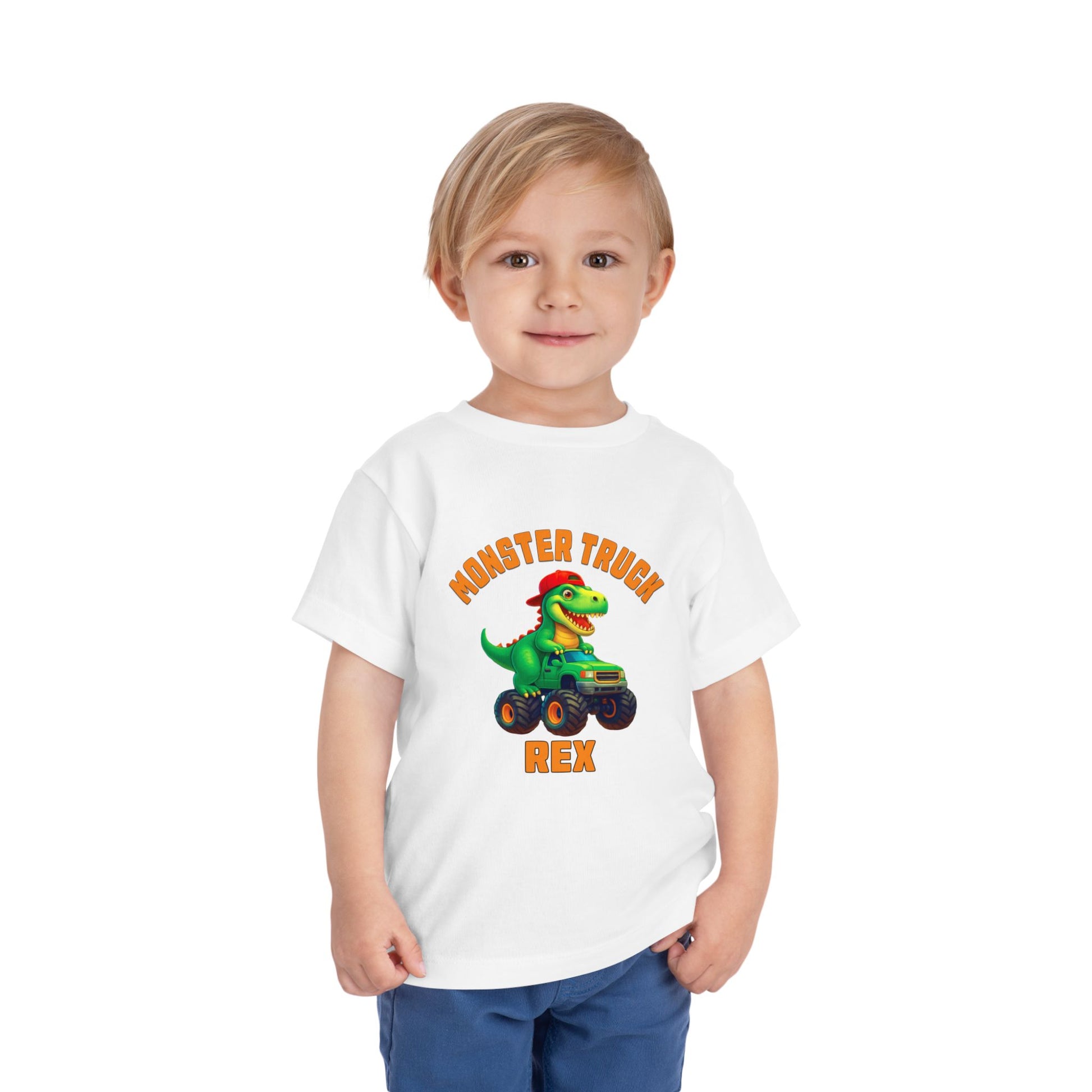 A smiling blonde-haired child wears the Monster Truck Rex T-Shirt 🛻🦕 – Toddler Boys Tee, featuring a cartoon dinosaur in a monster truck, and stands against a white background.