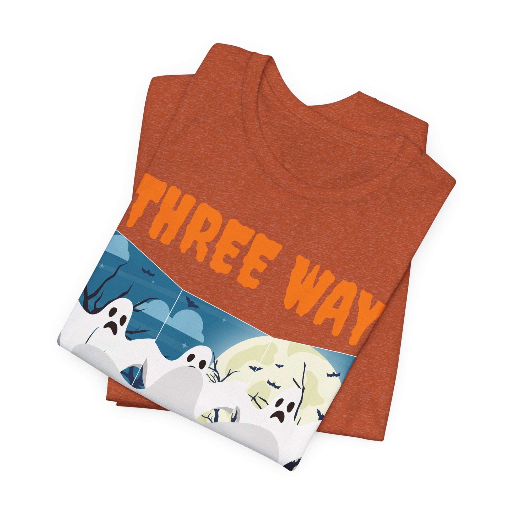 The Three-Way Mirror Ghost Tee combines a folded orange unisex jersey short-sleeve design with THREE WAY text and vibrant graphics of cartoon ghosts, mountains, bats, and a moon. Made from Airlume combed and ring-spun cotton for ultimate comfort, it’s a haunting twist on the viral TikTok trend.