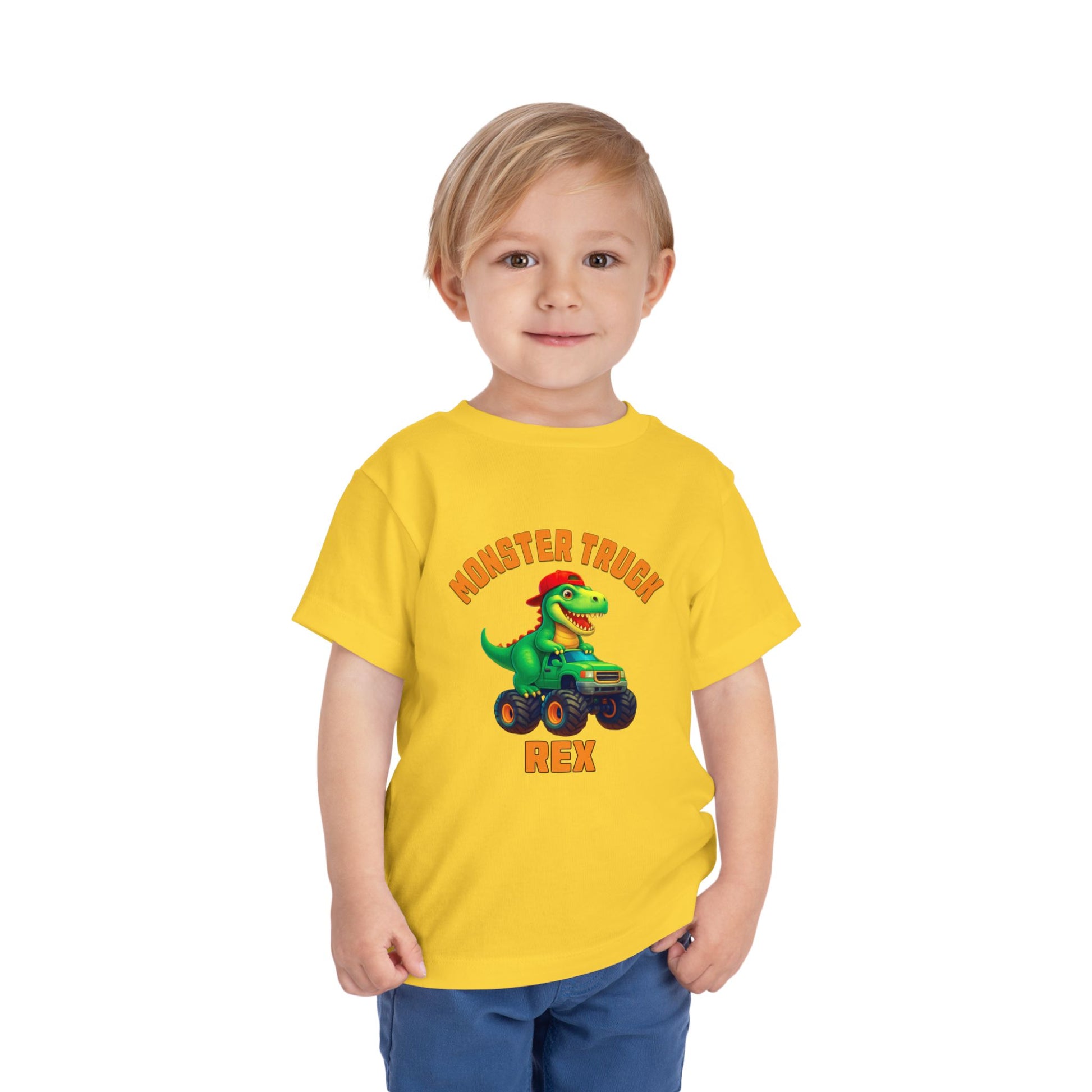 A young blonde child wears the Monster Truck Rex T-Shirt 🛻🦕 – Toddler Boys Tee, featuring a cartoon dinosaur in a monster truck with Monster Truck Rex text, against a plain white background.