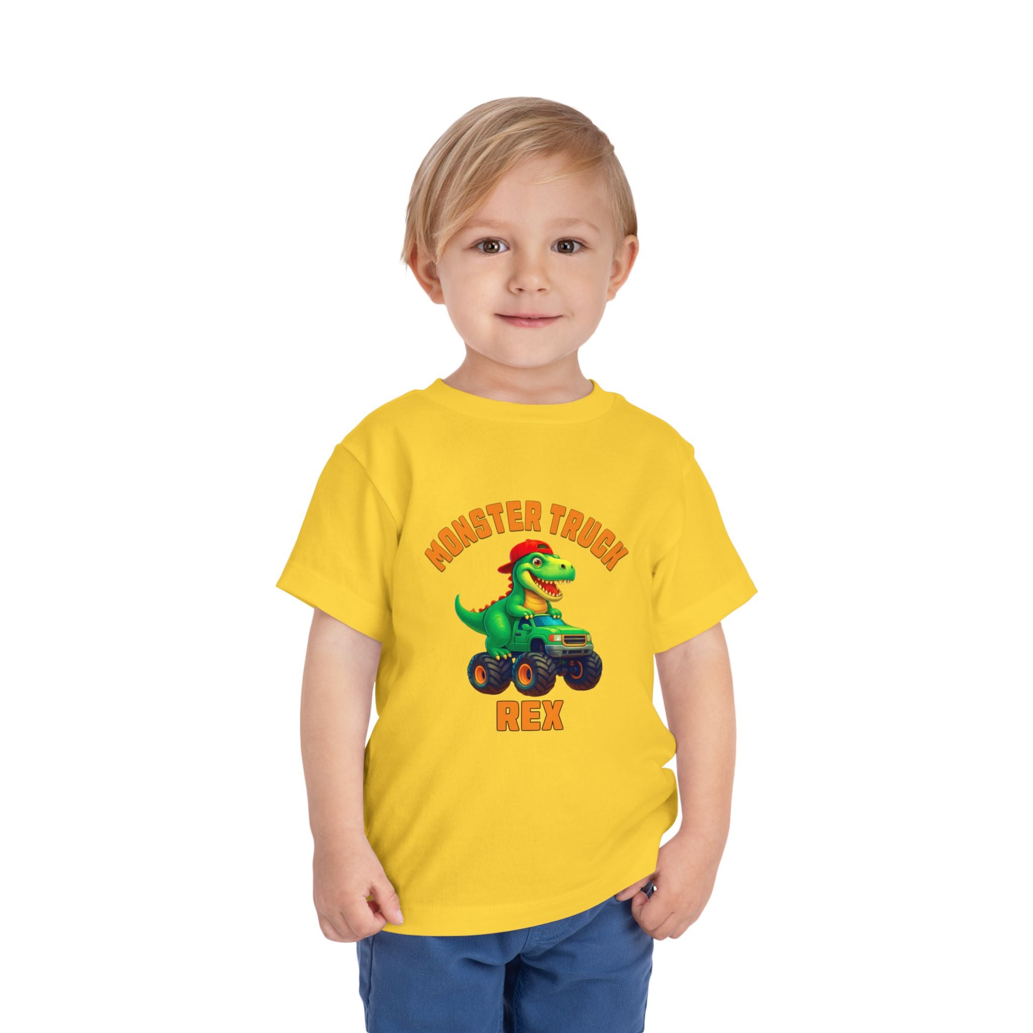 A young blonde child wears the Monster Truck Rex T-Shirt 🛻🦕 – Toddler Boys Tee, featuring a cartoon dinosaur in a monster truck with Monster Truck Rex text, against a plain white background.