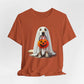 The Ghostly Pup Halloween T-Shirt features a cute dog dressed as a ghost with a sheet over its head and holding a pumpkin-shaped trick-or-treat bucket. This adorable design comes on a unisex jersey short sleeve tee.