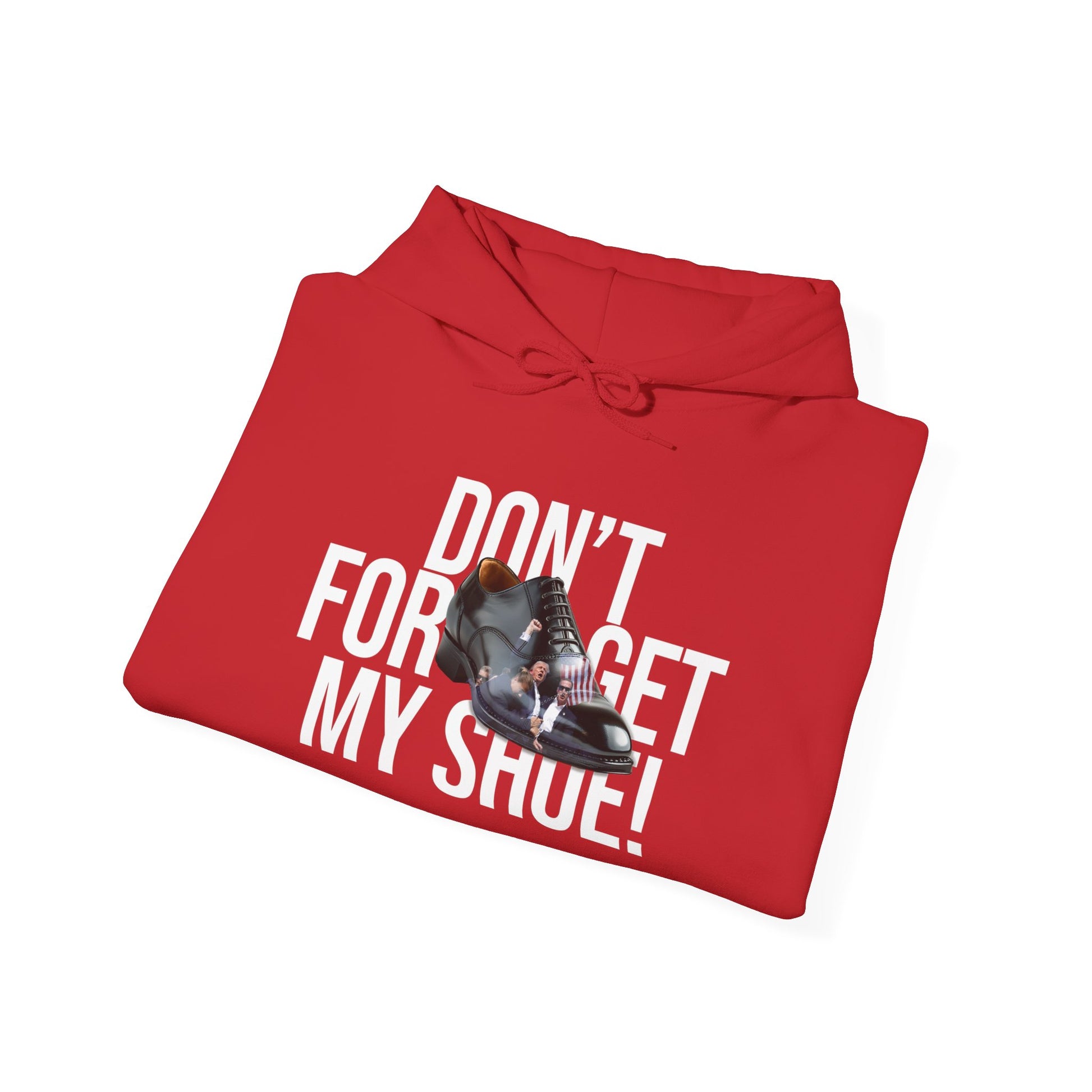 The Unisex Heavy Blend™ Hooded Sweatshirt, crafted from ethically grown US cotton, features a vibrant red color and white text saying DONT FORGET MY SHOE! It has a design of a black formal shoe with red laces and accents, emphasizing both style and comfort.