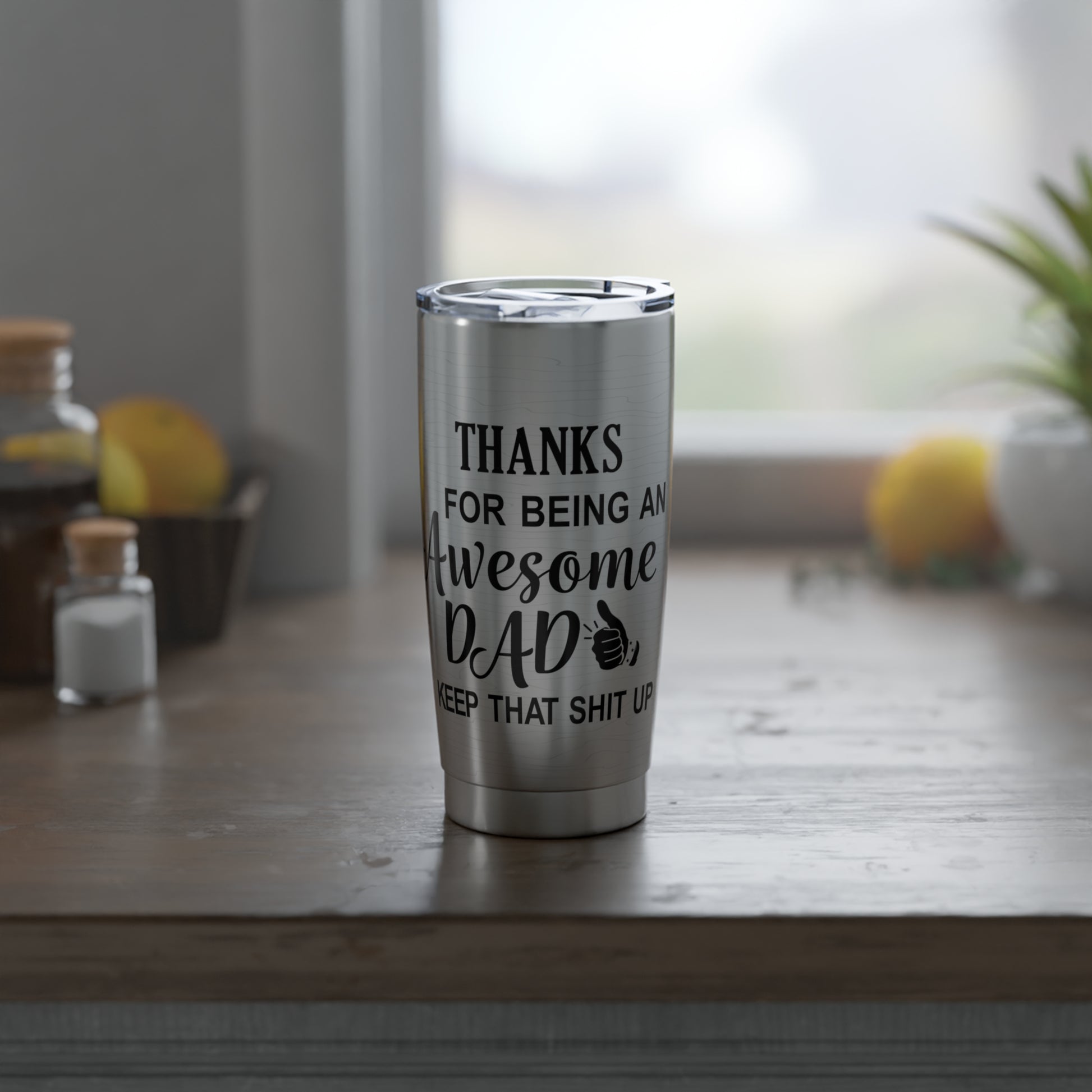 The “Thanks for Being an Awesome Dad” 20oz Stainless Steel Tumbler sits on a wooden table in a kitchen, making a funny and perfect Father’s Day gift for dads.