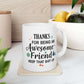 White ceramic mug with a humorous message thanking an awesome friend, decorated with festive elements like snowflakes and trees.