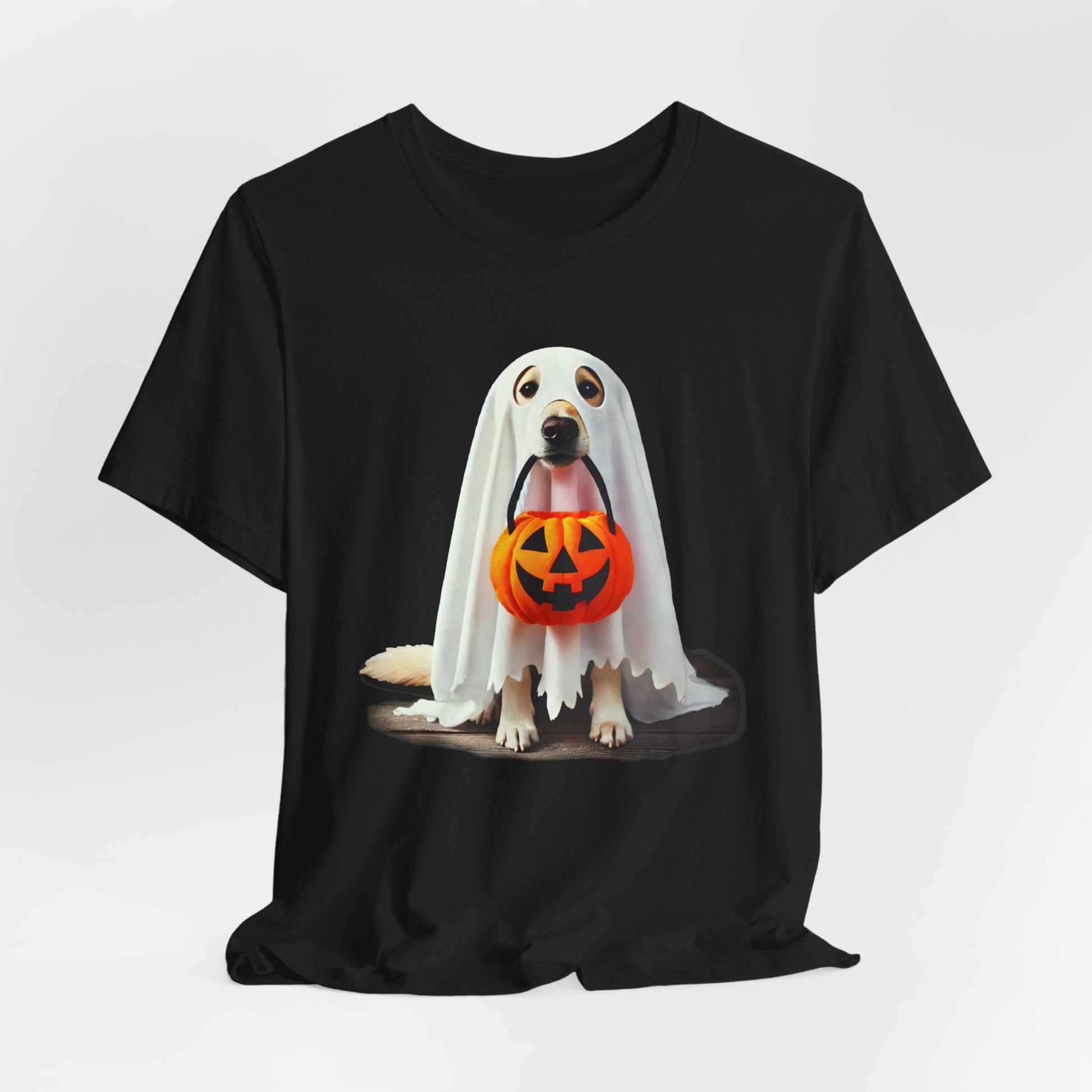 The Ghostly Pup Halloween T-Shirt features a cute ghost dog in a white sheet with eye holes, holding an orange jack-o-lantern bucket, perfect for unisex spooky style.