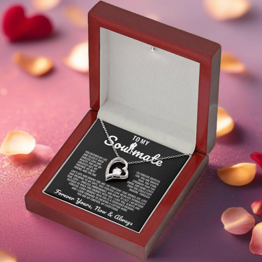 Silver heart pendant necklace with a sparkling crystal, displayed in a wooden gift box with a romantic message for a soulmate, surrounded by rose petals.