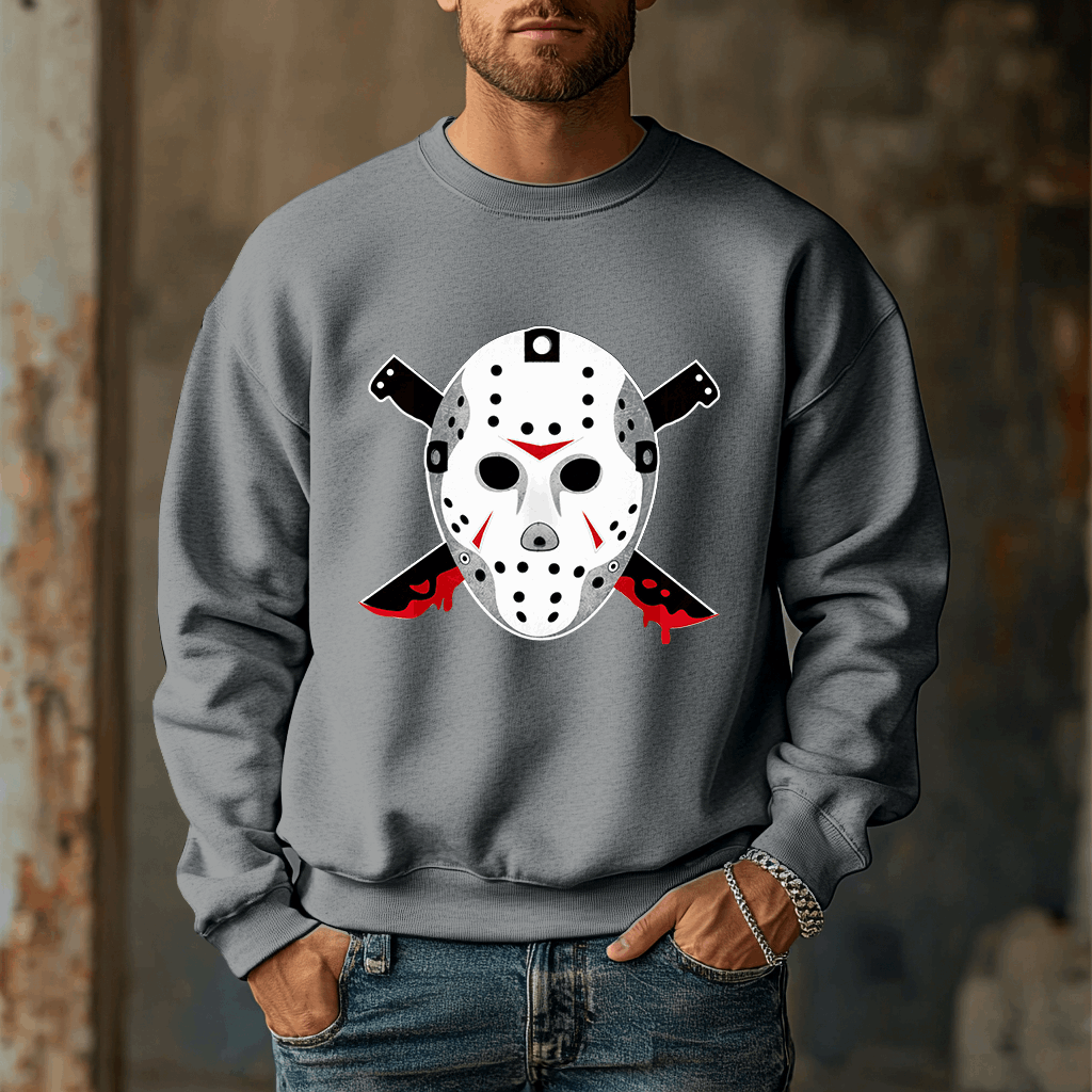A man wears the Voorhees 13 Iconic Horror Sweatshirt, featuring a hockey mask and bloody knives. The blurred rustic background enhances the eerie vibe, perfect for horror enthusiasts.