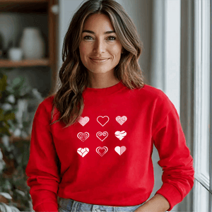 Woman wearing a red sweatshirt featuring a minimalist heart design with various artistic heart patterns in white.