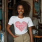 Woman wearing a white-shirt featuring a heart-shaped word art design with kindness-related words in white text.