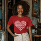 Woman wearing a red t-shirt featuring a heart-shaped word art design with kindness-related words in white text.