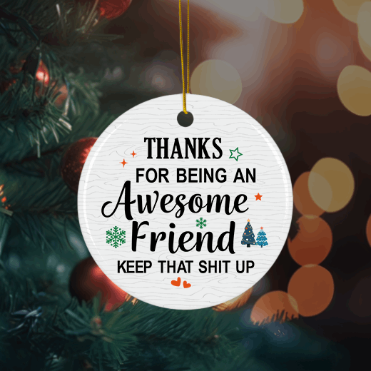 Round white Christmas ornament with a humorous appreciation message for an awesome friend, decorated with festive icons and hung on a holiday tree.