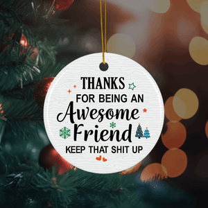 Round white Christmas ornament with a humorous appreciation message for an awesome friend, decorated with festive icons and hung on a holiday tree.