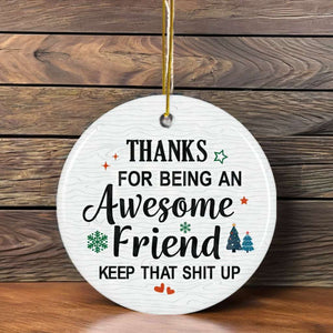 Round white Christmas ornament with a humorous appreciation message for an awesome friend, decorated with festive icons and hung on a holiday tree.