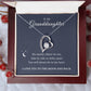 The To My Granddaughter - Forever Love Necklace with Heartfelt Message Card features a heart-shaped pendant with a CZ crystal and small inner heart on a chain, elegantly crafted in white gold finish. It comes in an open jewelry box surrounded by frosted red berries, with the message: I love you to the moon and back.