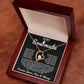 Gold heart pendant necklace with a sparkling crystal, displayed in a wooden gift box with a romantic message for a soulmate, surrounded by rose petals.