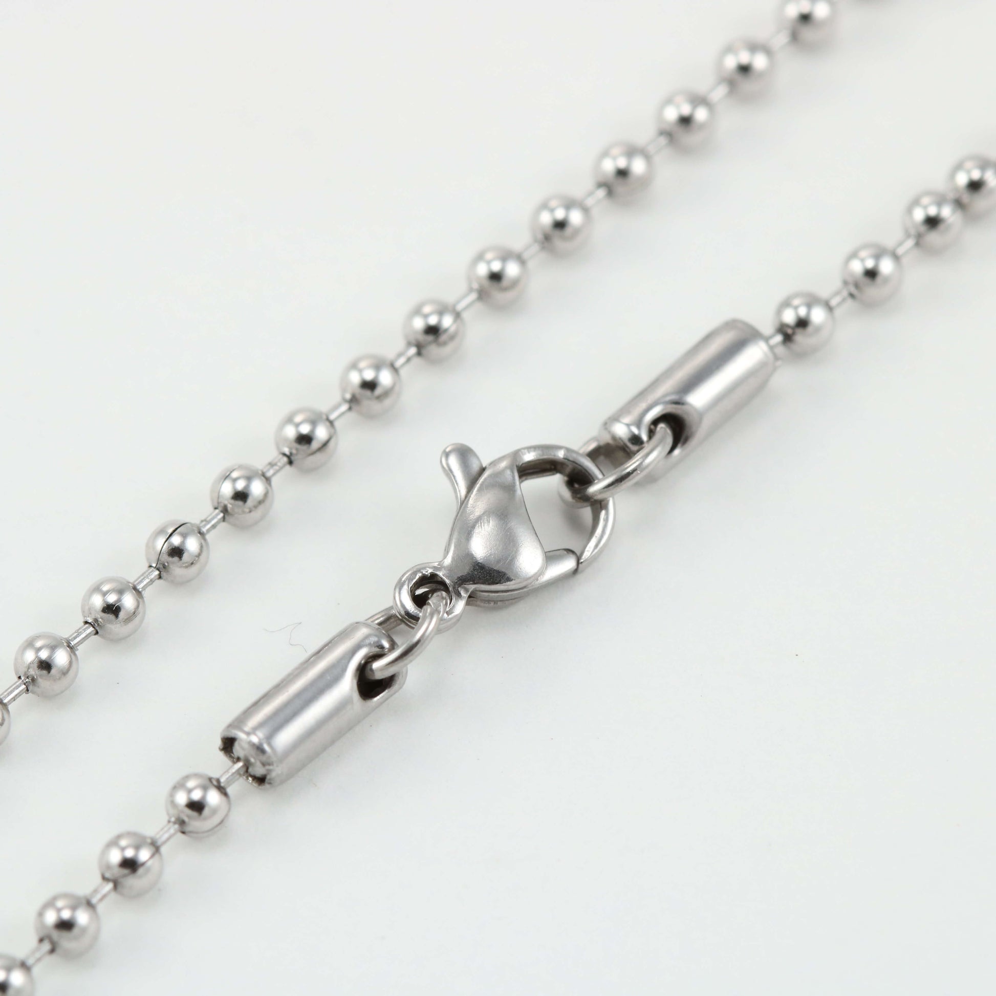 Close-up of the Replacement Attachment, a silver ball chain necklace accessory with a lobster clasp closure, displayed on a white background.