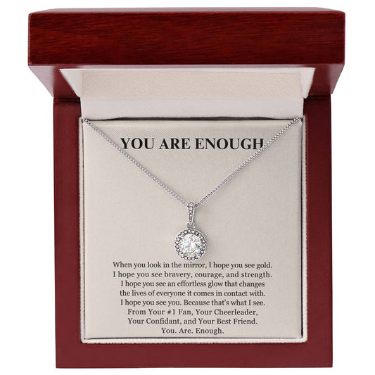The Eternal Hope Necklace - You Are Enough features a sparkling silver circular charm in an open wooden box. The lid displays YOU ARE ENOUGH with a motivating message, making this an inspiring piece of self-love jewelry.