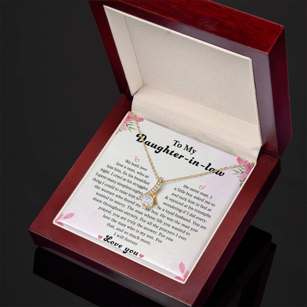 A wooden box with the To My Daughter-in-Law heartfelt message card, featuring pink flowers, contains the Alluring Beauty necklace boasting a moon and heart pendant in 14k white gold finish.