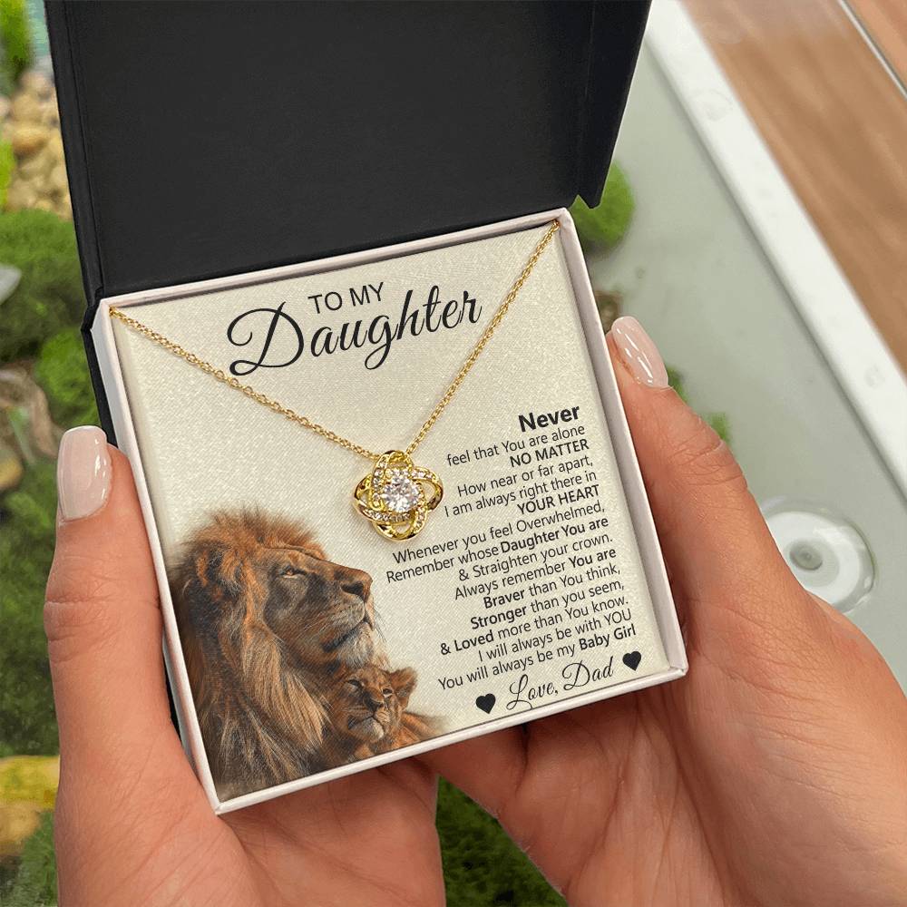 A person holds an open To My Daughter – Love Knot Necklace with Lion & Cub Message Card, featuring a heartfelt message and pendant—an ideal gift for daughters.