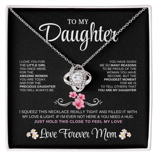 Elegant silver love knot necklace with a sparkling crystal, displayed in a black gift box featuring a heartfelt message from a mother to her daughter.