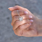 A manicured hand holds a delicate silver Love Knot Necklace with a sparkling round pendant—an ideal gift, presented on a “To My Daughter” Lion & Cub message card.