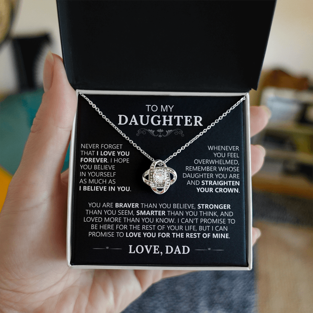 A hand holds an open box displaying the To My Daughter - Love Knot Necklace in 14k White Gold. Inside the lid is a heartfelt message from a father, making it the ideal gift to express love and encouragement to a daughter.