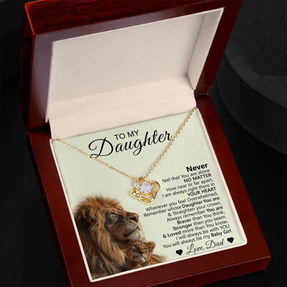 The To My Daughter – Love Knot Necklace with Lion & Cub Message Card is shown in a wooden box, featuring a gold necklace and a card with a heartfelt message plus an image of a lion and cub in the lower left corner.