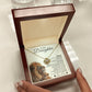 A person holds an open wooden box with the To My Daughter – Love Knot Necklace, featuring a lion & cub message card with two lions and an inspirational note from dad.