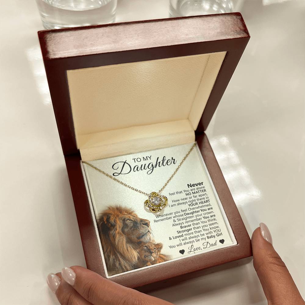A person holds an open wooden box with the To My Daughter – Love Knot Necklace, featuring a lion & cub message card with two lions and an inspirational note from dad.