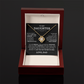 The To My Daughter - Love Knot Necklace features a gold knot pendant in a wooden jewelry box. Inside the lid, a card says To my Daughter with an encouraging message from Dad, symbolizing their strong bond.