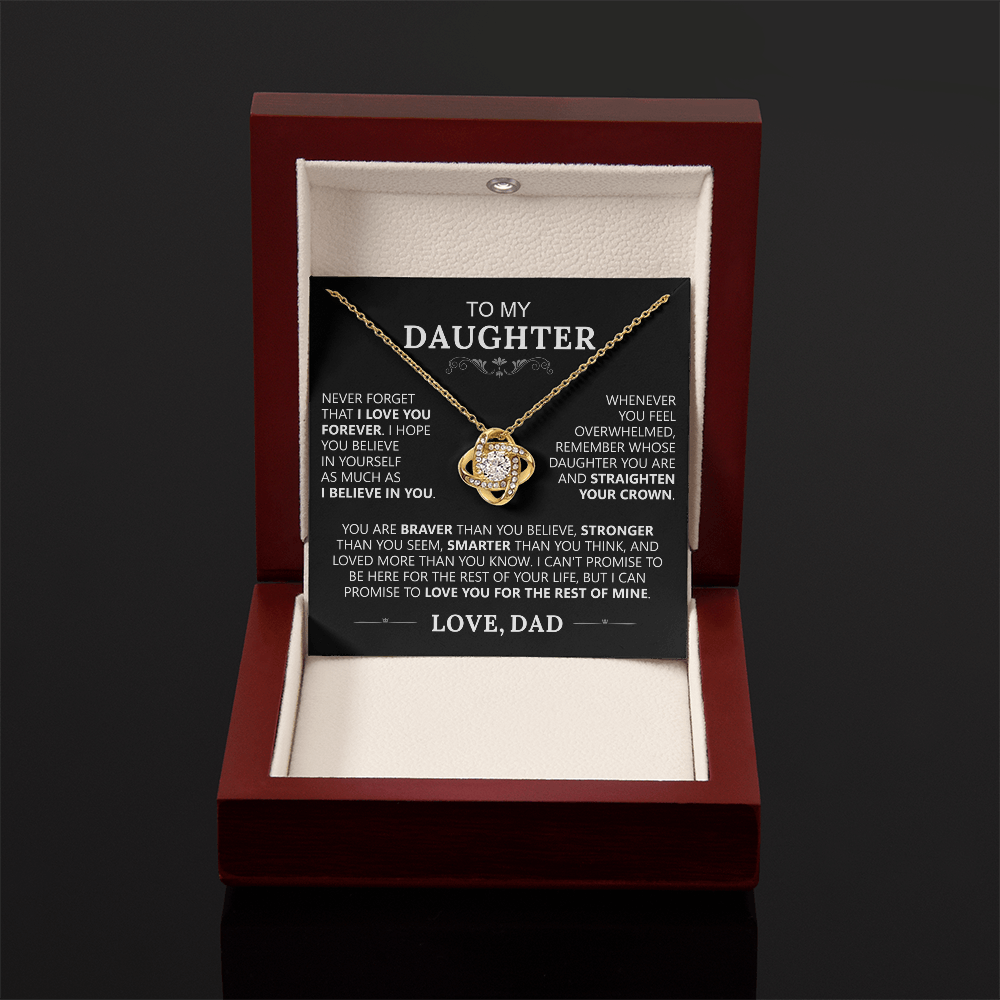 The To My Daughter - Love Knot Necklace features a gold knot pendant in a wooden jewelry box. Inside the lid, a card says To my Daughter with an encouraging message from Dad, symbolizing their strong bond.