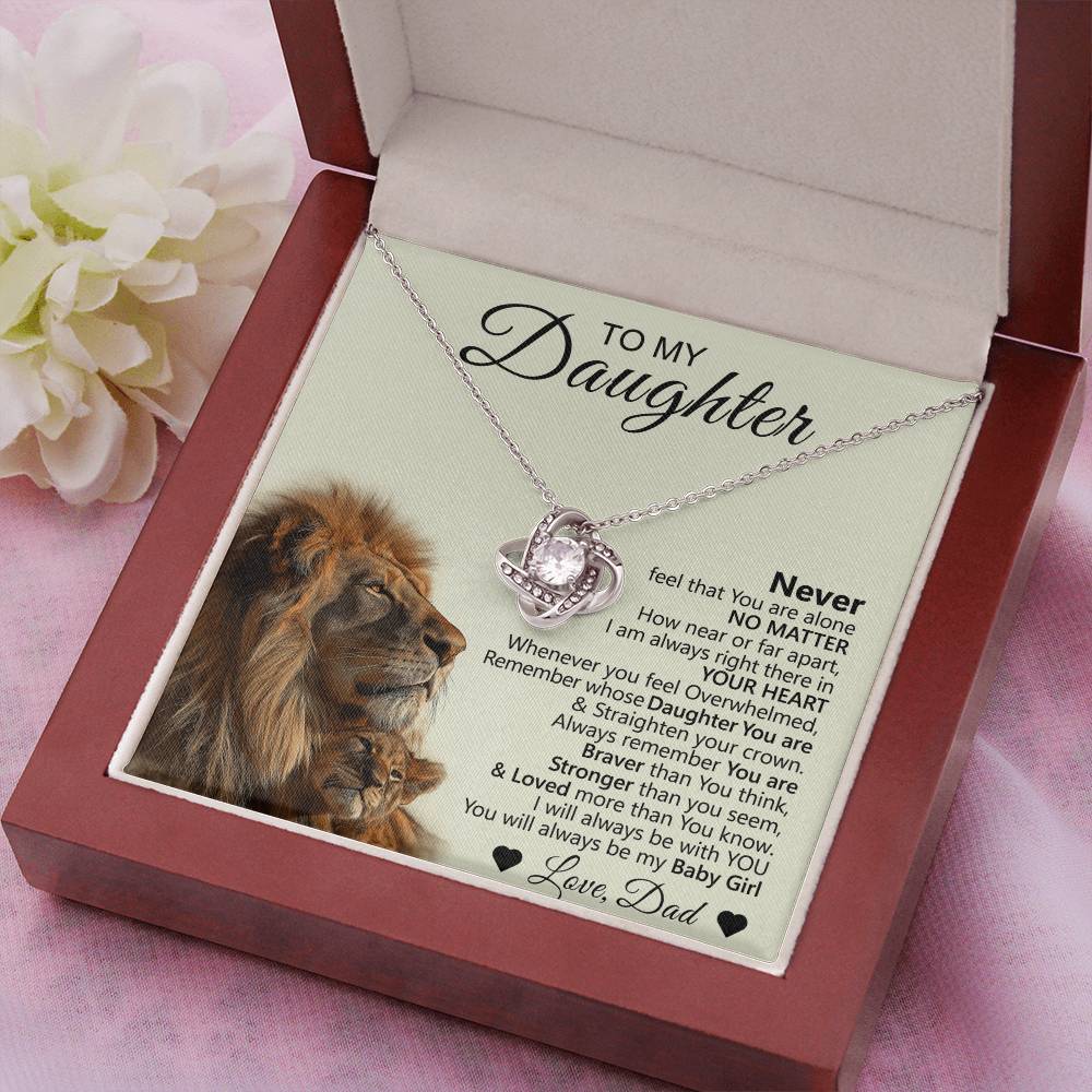 A jewelry box contains the To My Daughter – Love Knot Necklace with a Lion & Cub message card from a father, featuring an image of a lion and cub, words of encouragement, and a white flower beside the gift for daughter.