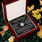 The To My Daughter - Love Knot Necklace comes in a wooden box with an inspirational message from Dad, set amidst green grass and yellow leaves. It celebrates their unbreakable bond and inspires strength, love, and confidence.