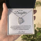 A hand holds an open box with the To My Daughter: Forever Connected Message Card & Love Knot Necklace Set inside. The message card conveys a fathers pride and love for his daughter. Green plant leaves appear in the background.